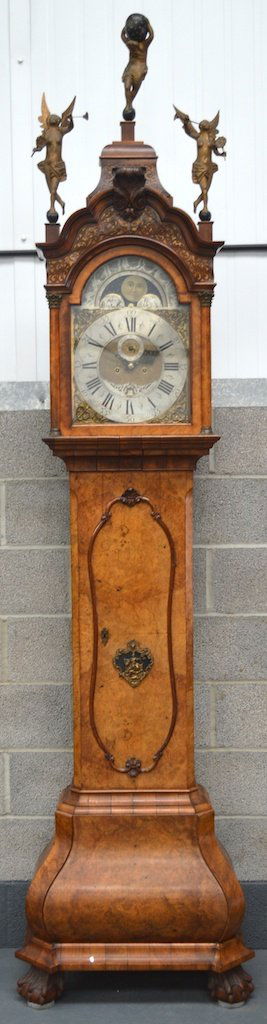 A GOOD 18TH CENTURY DUTCH BURR WALNUT LONGCASE CLOCK by: A GOOD 18TH CENTURY DUTCH BURR WALNUT LONGCASE CLOCK by Paulus Bramer, Amsterdam, the hood surmounted with two semi clad figures and atlas, the silvered dial with painted moonphase & subsidiary featur