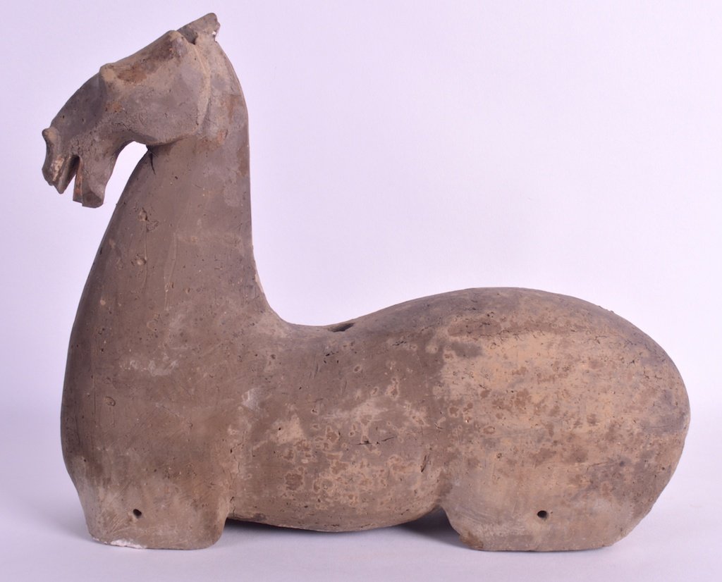 AN UNUSUAL CHINESE HAN DYNASTY GREY POTTERY MODEL OF A: AN UNUSUAL CHINESE HAN DYNASTY GREY POTTERY MODEL OF A HORSE 206BC to 220AD modelled recumbent with mouth open. 11.75ins wide.