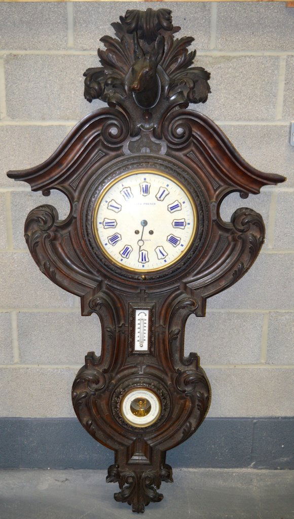 AN UNUSUAL LARGE 19TH CENTURY BLACK FOREST CARVED WALL: AN UNUSUAL LARGE 19TH CENTURY BLACK FOREST CARVED WALL CLOCK with deer head terminal, barometer and thermometer functions, the dial with blue enamel numerals. 5ft 7ins x 2ft 11ins.