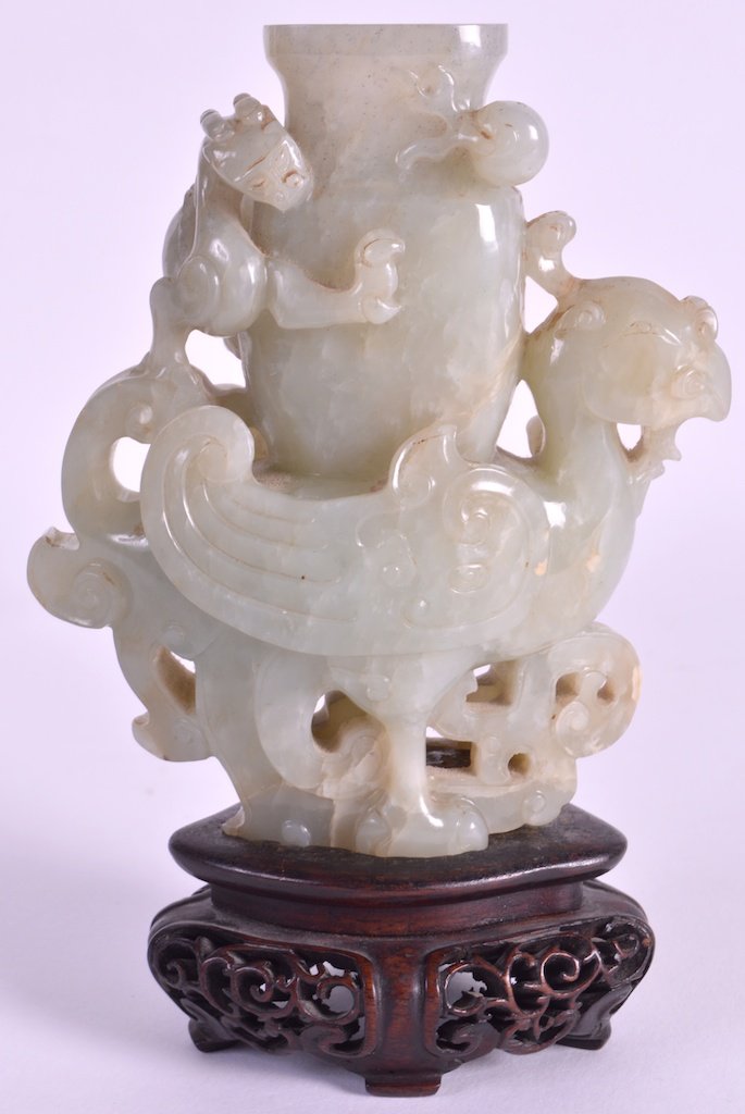 A FINE 18TH CENTURY CHINESE CARVED GREEN JADE ‘PHOENIX’: A FINE 18TH CENTURY CHINESE CARVED GREEN JADE ‘PHOENIX’ VASE Qianlong, modelled standing with elaborately carved feathers, the vase surmounted with clambering dragons in pursuit of a flaming pearl