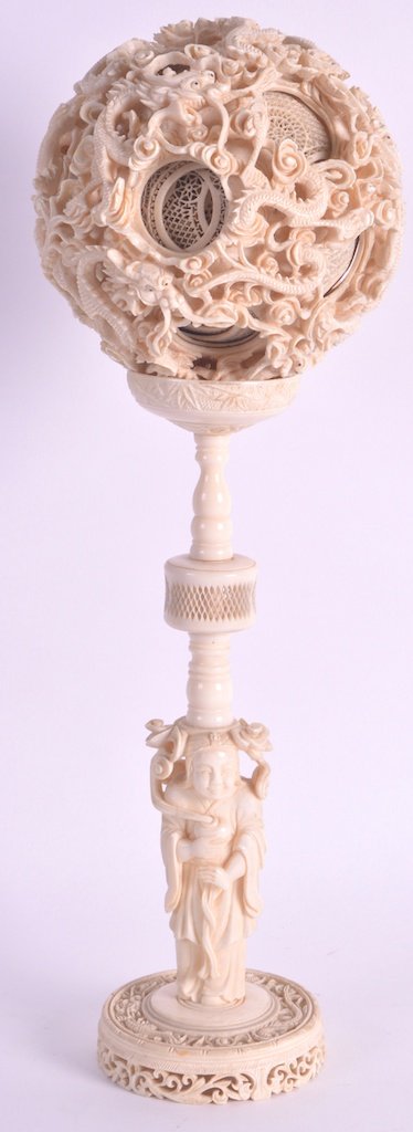 A FINE 19TH CENTURY CHINESE CANTON IVORY PUZZLE BALL ON: A FINE 19TH CENTURY CHINESE CANTON IVORY PUZZLE BALL ON STAND of huge proportions, carved with extensive dragons amongst clouds, the base formed as a standing female in flowing robes. Overall 1ft 4ins