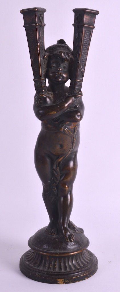 GUSTAVE JOSEPH CHERET (C1890) A LATE 19TH CENTURY: GUSTAVE JOSEPH CHERET (C1890) A LATE 19TH CENTURY BRONZE TWIN HANDLED FIGURAL CANDLEABRA modelled as a female holding aloft two sconces, upon a circular base. 1ft 4ins high. £100-150.