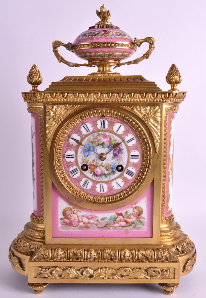 A 19TH CENTURY FRENCH ORMOLU AND PORCELAIN MANTEL CLOCK: A 19TH CENTURY FRENCH ORMOLU AND PORCELAIN MANTEL CLOCK inset with Sevres style pink painted plaques, depicting putti and flowers. 1ft 1.5ins high.