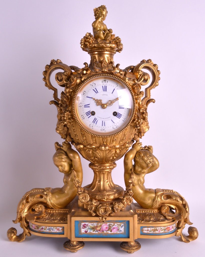 A FINE LOUIS XVI CENTURY FRENCH ORMOLU AND SEVRES: A FINE LOUIS XVI CENTURY FRENCH ORMOLU AND SEVRES PORCELAIN MANTEL CLOCK by Lepine, modelled as two figures holding aloft an urn, flanked by porcelain panels of flowers. 1ft 8.5ins x 1ft 3.5ins.