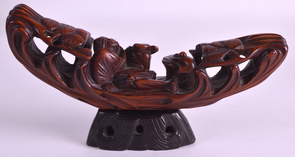 A 19TH CENTURY CHINESE CARVED ROOTWOOD FIGURAL GROUP: A 19TH CENTURY CHINESE CARVED ROOTWOOD FIGURAL GROUP depicting a reclining buddhist upon a raft. 7ins long.