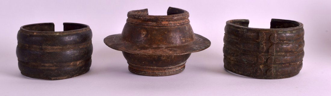 AN EARLY 20TH CENTURY WEST AFRICAN BRONZE TRIBAL CUFF: AN EARLY 20TH CENTURY WEST AFRICAN BRONZE TRIBAL CUFF BRACLET together with two other similar cuff bracelets. Largest 4.75ins wide. (3)