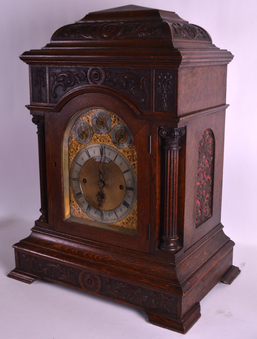 A HUGE VICTORIAN CARVED OAK BRACKET CLOCK by Sir John: A HUGE VICTORIAN CARVED OAK BRACKET CLOCK by Sir John Bennett Ltd, with wall mount, profusely carved with foliage and flanked by corinthian columns. Clock 2ft 2ins high.