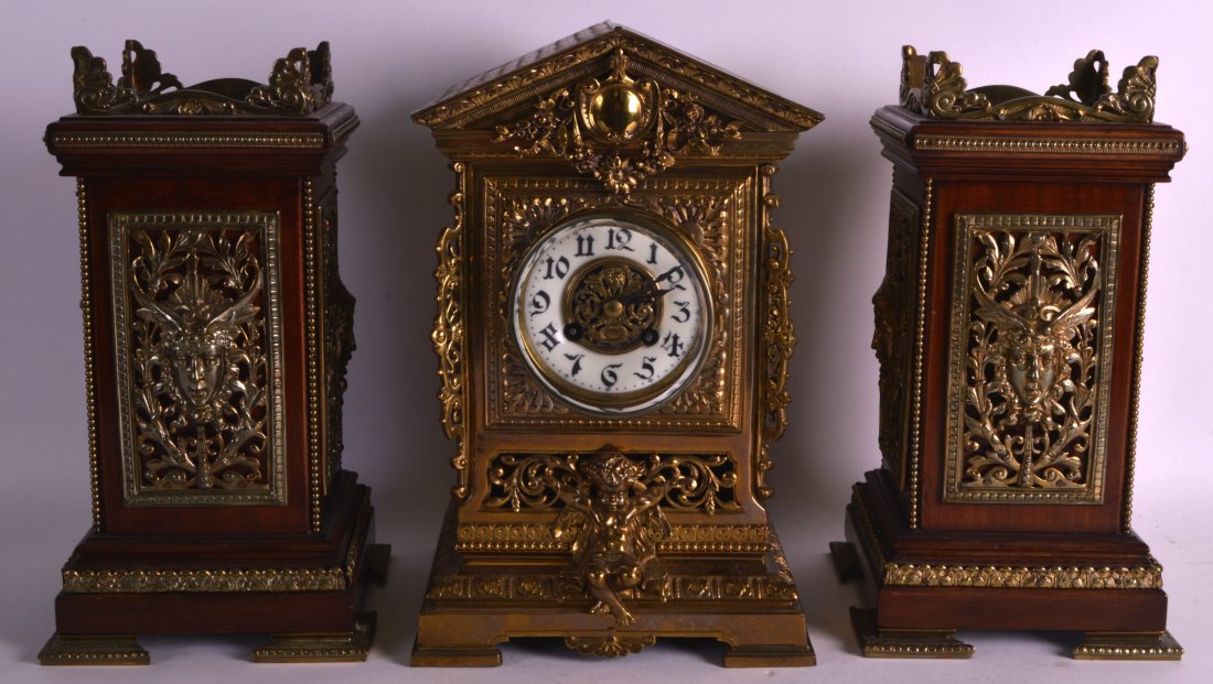 A LATE 19TH CENTURY FRENCH CLOCK GARNITURE the mantel: A LATE 19TH CENTURY FRENCH CLOCK GARNITURE the mantel with arched top, together with a pair of mahogany brass bound side vases. (3)