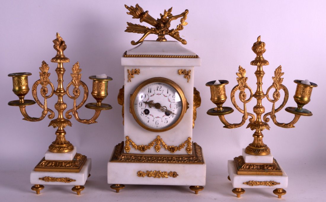 A LATE 19TH CENTURY FRENCH MARBLE CLOCK GARNITURE the: A LATE 19TH CENTURY FRENCH MARBLE CLOCK GARNITURE the mantel clock with rams mask heads and painted dial. Mantel 12.5ins high.