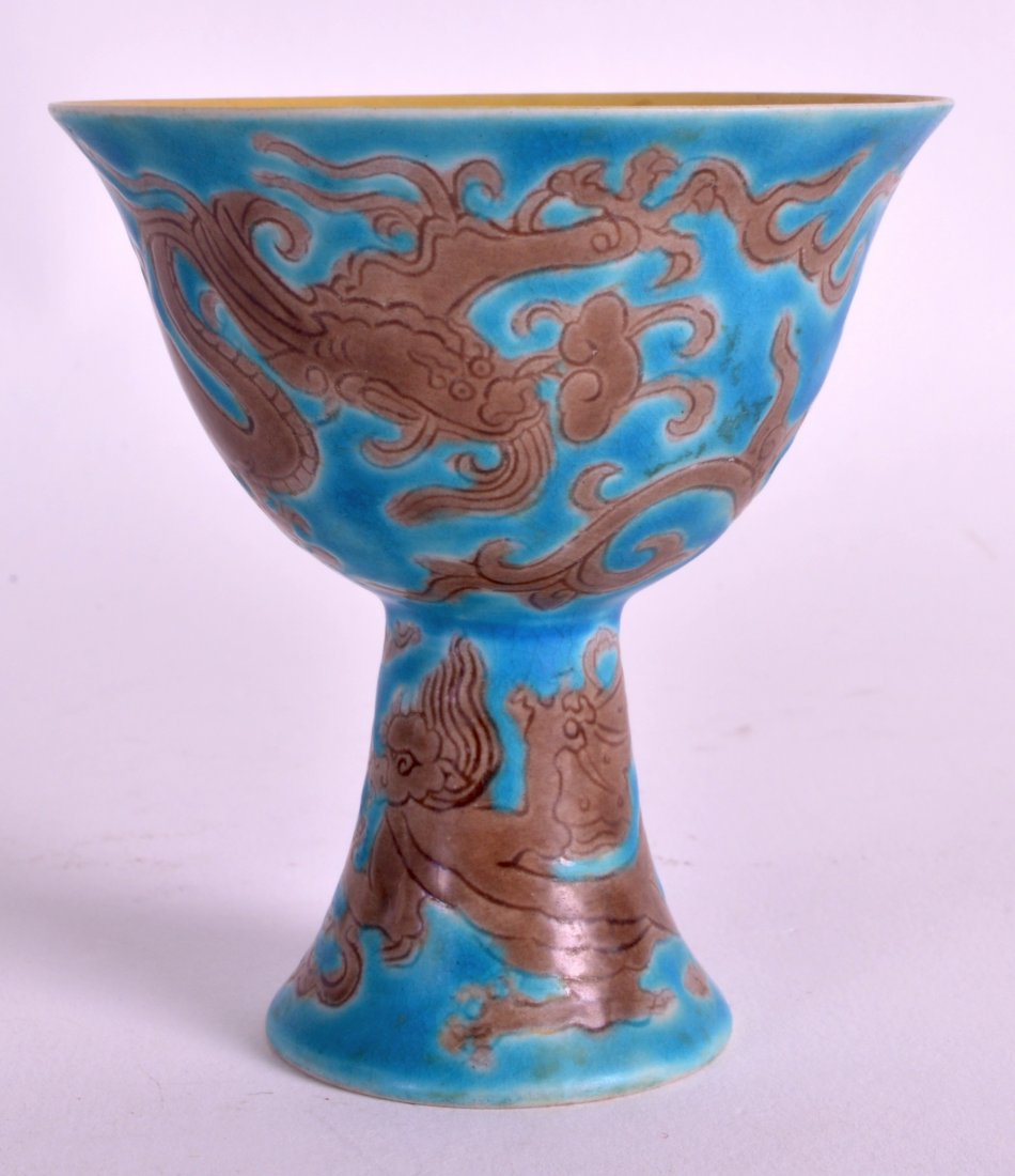 A CHINESE QING DYNASTY BLUE GLAZED PORCELAIN STEM CUP: A CHINESE QING DYNASTY BLUE GLAZED PORCELAIN STEM CUP bearing Zhengdhe marks to base, decorated with dragons, with an internal yellow ground. 3.25ins high.