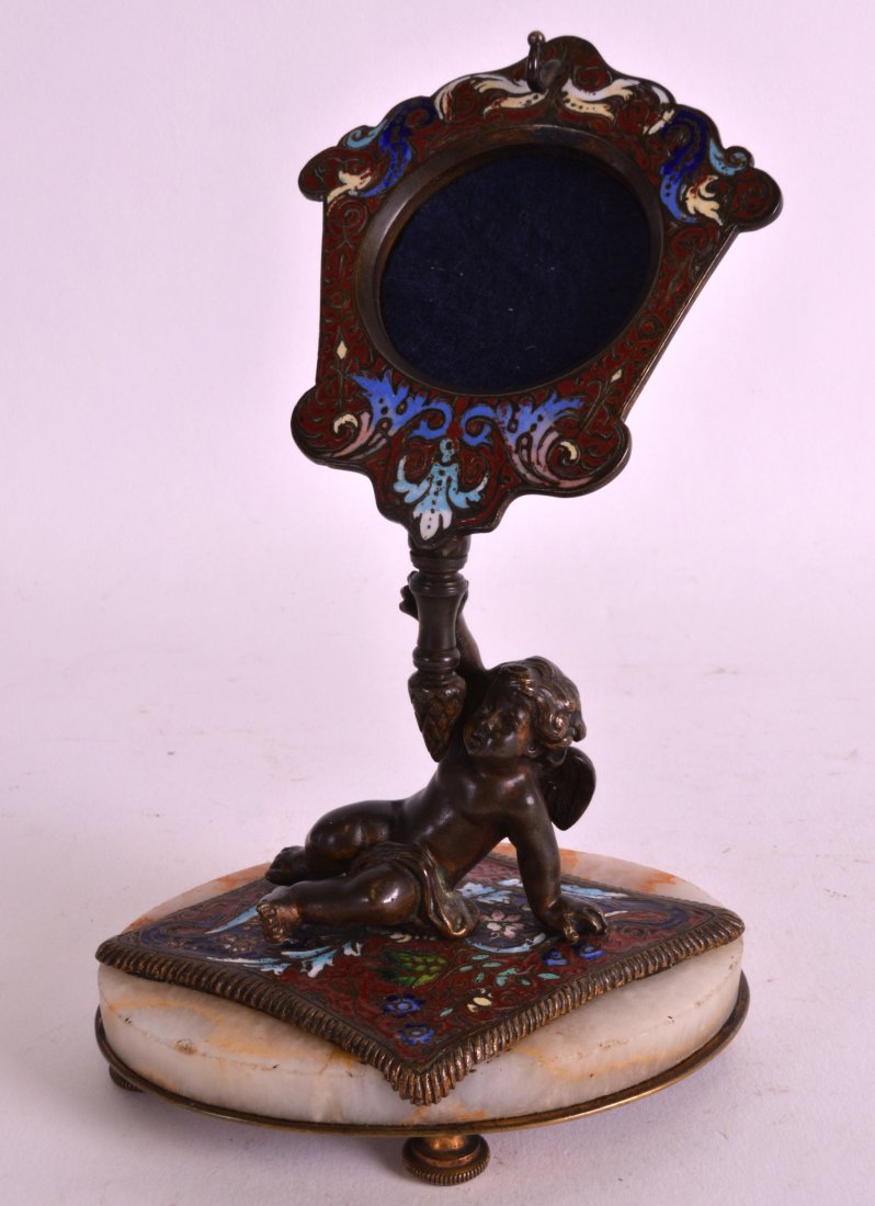 A LATE 19TH CENTURY FRENCH CHAMPLEVE ENAMEL POCKET: A LATE 19TH CENTURY FRENCH CHAMPLEVE ENAMEL POCKET WATCH HOLDER modelled as a cherub holding aloft a frame. 5.75ins high.