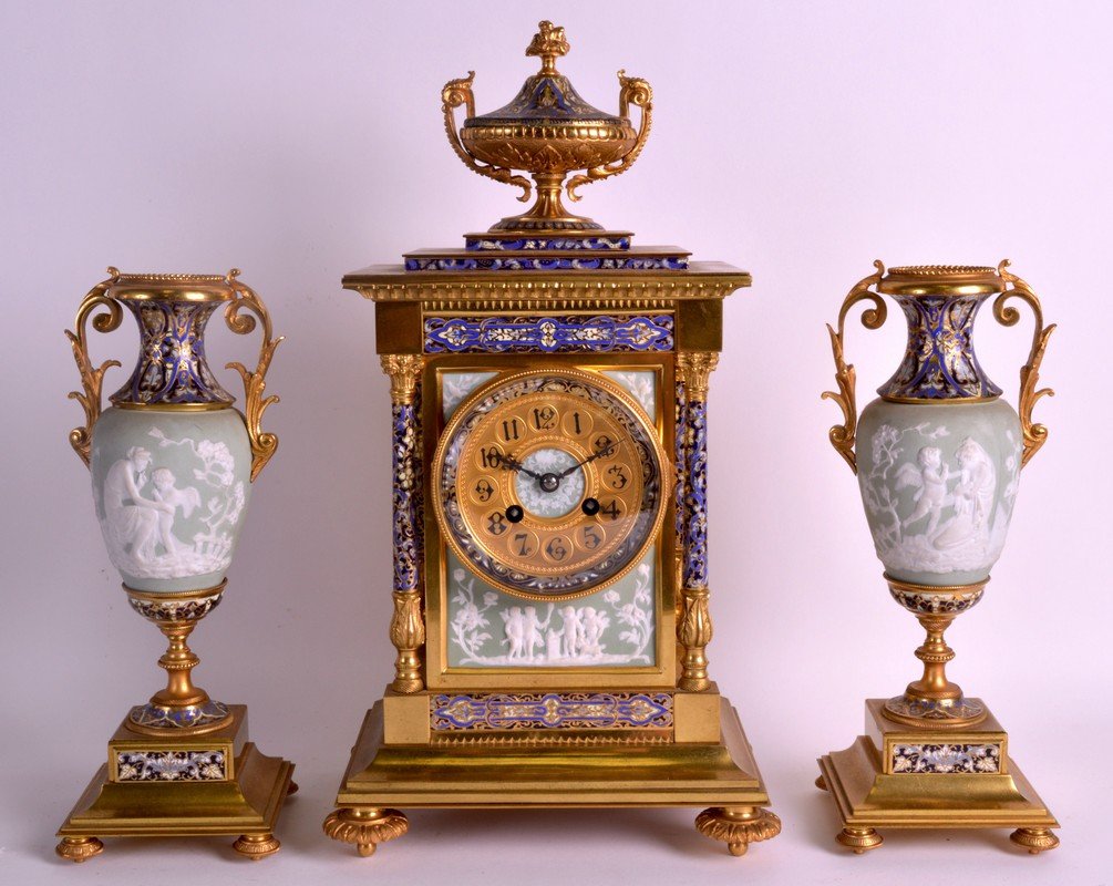 A STUNNING 19TH CENTURY FRENCH CHAMPLEVE ENAMEL AND: A STUNNING 19TH CENTURY FRENCH CHAMPLEVE ENAMEL AND BRONZE CLOCK GARNITURE unusually inset with Wedgwood parian glazed panels depicting classical figures. Clock 1ft 6ins x 8.25ins. (3)
