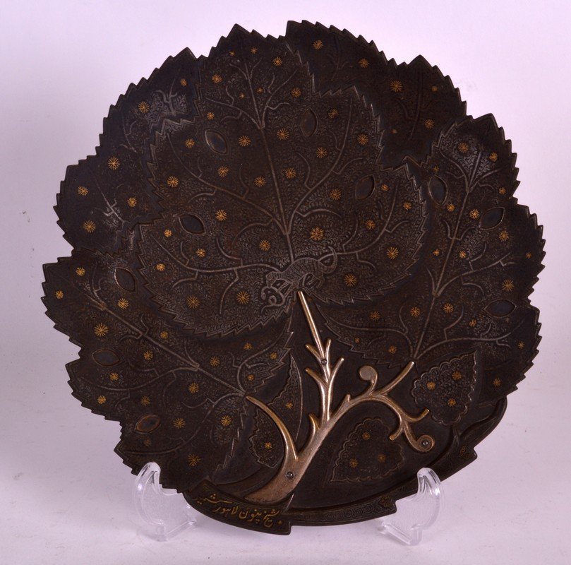 A FINE MID 19TH CENTURY ISLAMIC SILVER AND GOLD INLAID: A FINE MID 19TH CENTURY ISLAMIC SILVER AND GOLD INLAID IRON DISH in the form of a leaf, decorated with animals and motifs. Signed. 9.25ins wide.