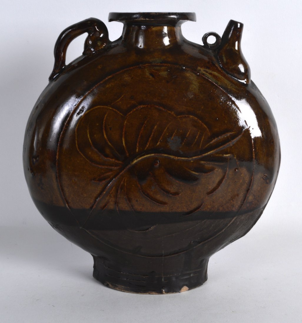 AN EARLY KOREAN TREACLE GLAZED MOON FLASK incised with: AN EARLY KOREAN TREACLE GLAZED MOON FLASK incised with a central floral vine, with loop handle. 8Ins high.