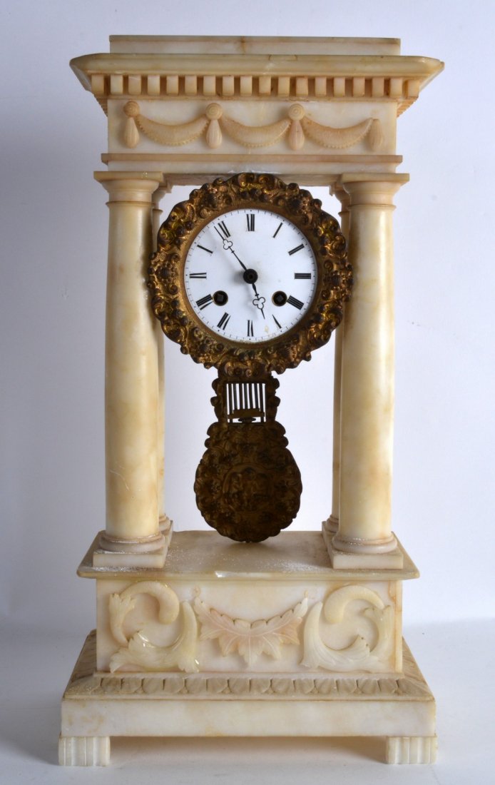 A LATE 19TH CENTURY CARVED ALABASTER PORTICO CLOCK with: A LATE 19TH CENTURY CARVED ALABASTER PORTICO CLOCK with white enamel dial and cylindrical supports. 1Ft 5.5ins high.