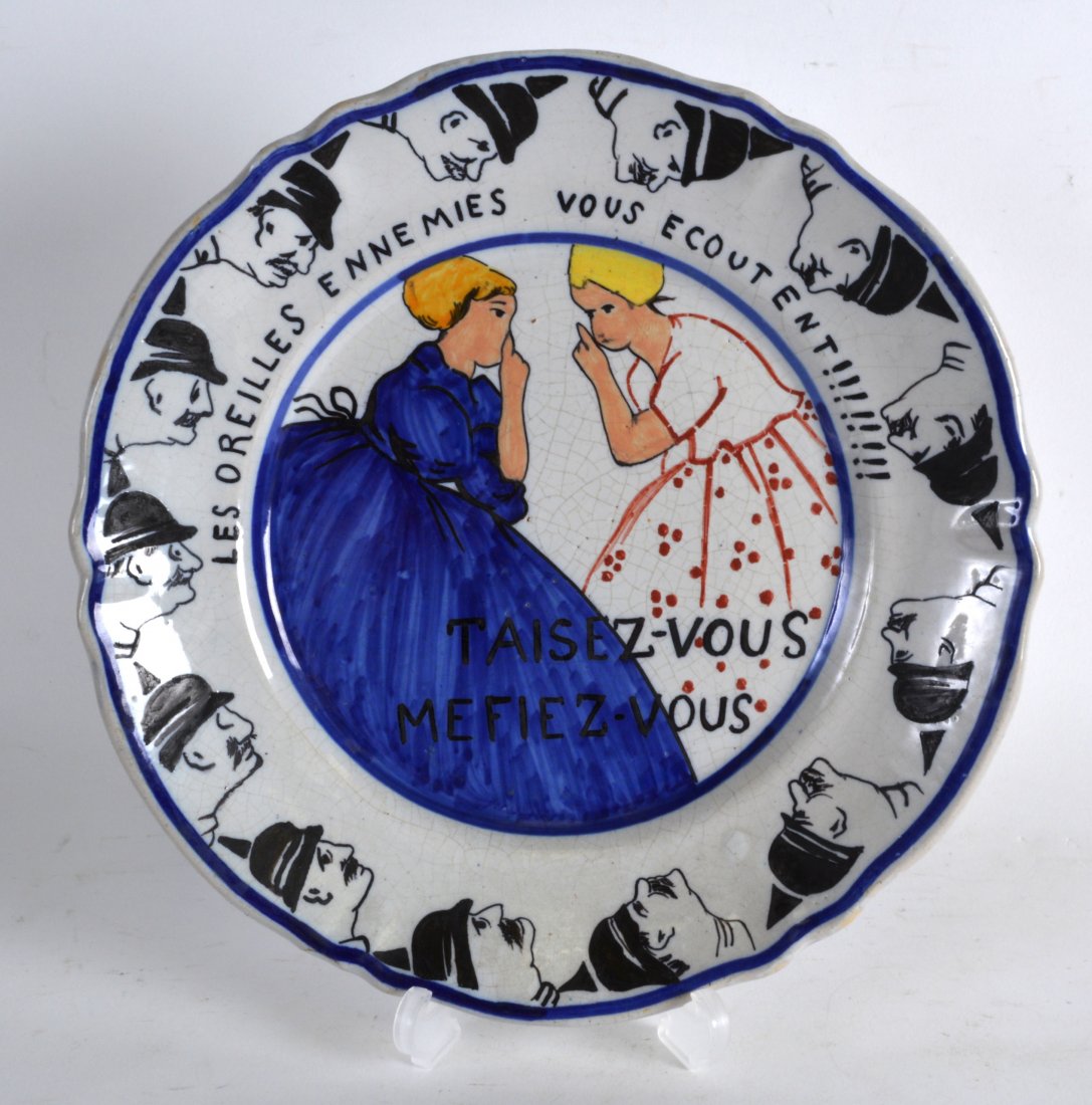 A RARE FRENCH QUIMPER FAIENCE POTTERY WW1 PLATE: A RARE FRENCH QUIMPER FAIENCE POTTERY WW1 PLATE depicting two children whispering, banded by German soldiers, the reverse with inscription. 9Ins diameter.
