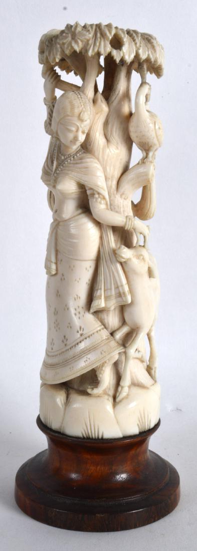 A 19TH CENTURY ANGLO INDIAN CARVED IVORY FIGURE OF A: A 19TH CENTURY ANGLO INDIAN CARVED IVORY FIGURE OF A FEMALE modelled beside a tree, her hand placed upon a goats head. Ivory 7.25ins high.