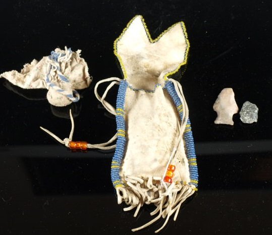 Early Plains Indian Medicine Pouch: Beaded and fringed hide pouch with "medicine" wrapped in old cloth fabric inside, likely corn also with two fetish arrowheads. Dimensions: 6 in. long x 3 in. wide.