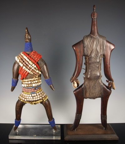 African Namji male & female dolls: 20th century A pair of African Namji dolls. Each on custom stand. The female covered with several strands of colorful beads. Each with diminutive head and inset eyes. The male wrapped in leather hide 