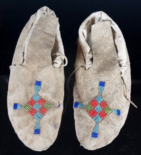 Pair of Crow Moccasins, Early 20th C.: Native American Crow beaded hide moccasins, parfleche soles, lined with old cotton cloth. Beaded with both plain and faceted seed beads. Length: 10.25 inches.