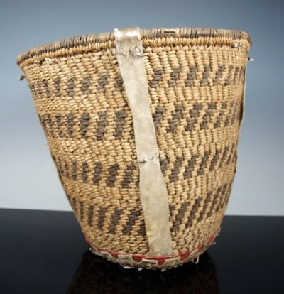 Native American Apache Burden Basket, Old: Nice, undersized, Apache burden basket, rawhide supports on four sides, tanned, patinated hide at the base, with cut-outs exposing red trade cloth beneath, in the typically artful style unique to the 