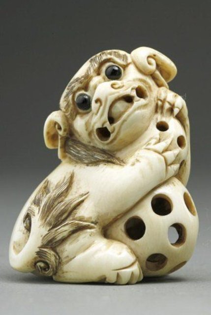 ANTIQUE JAPANESE IVORY NETSUKE OF A KARASHISHI: Holding two reticulated balls, one with a loose ball inside. Inlaid eyes and stained detail. Signature under the left foot. H: 1 5/8 in. Check your local wildlife laws to insure Federal compliance wit