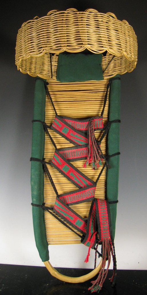 Pueblo Cradle with Basketry Sunshade: Pueblo infant cradle, constructed on a Willow frame with willow rods at the back, and a circular basketry sunshade woven of Sumac affixed with yarn. Decorated with commercial fabric and a native hand-