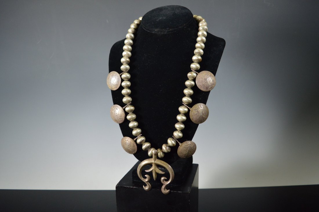 Navajo Coin Silver Squash Blossom Necklace: Navajo necklace composed of six 1940's "Walking Liberty" half-dollars, hammered silver beads, and a cast Naja (stamped "Sterling"). FROM THE ESTATE OF JOHN KOEHLER. Mr. Koehler, an avid collector, had