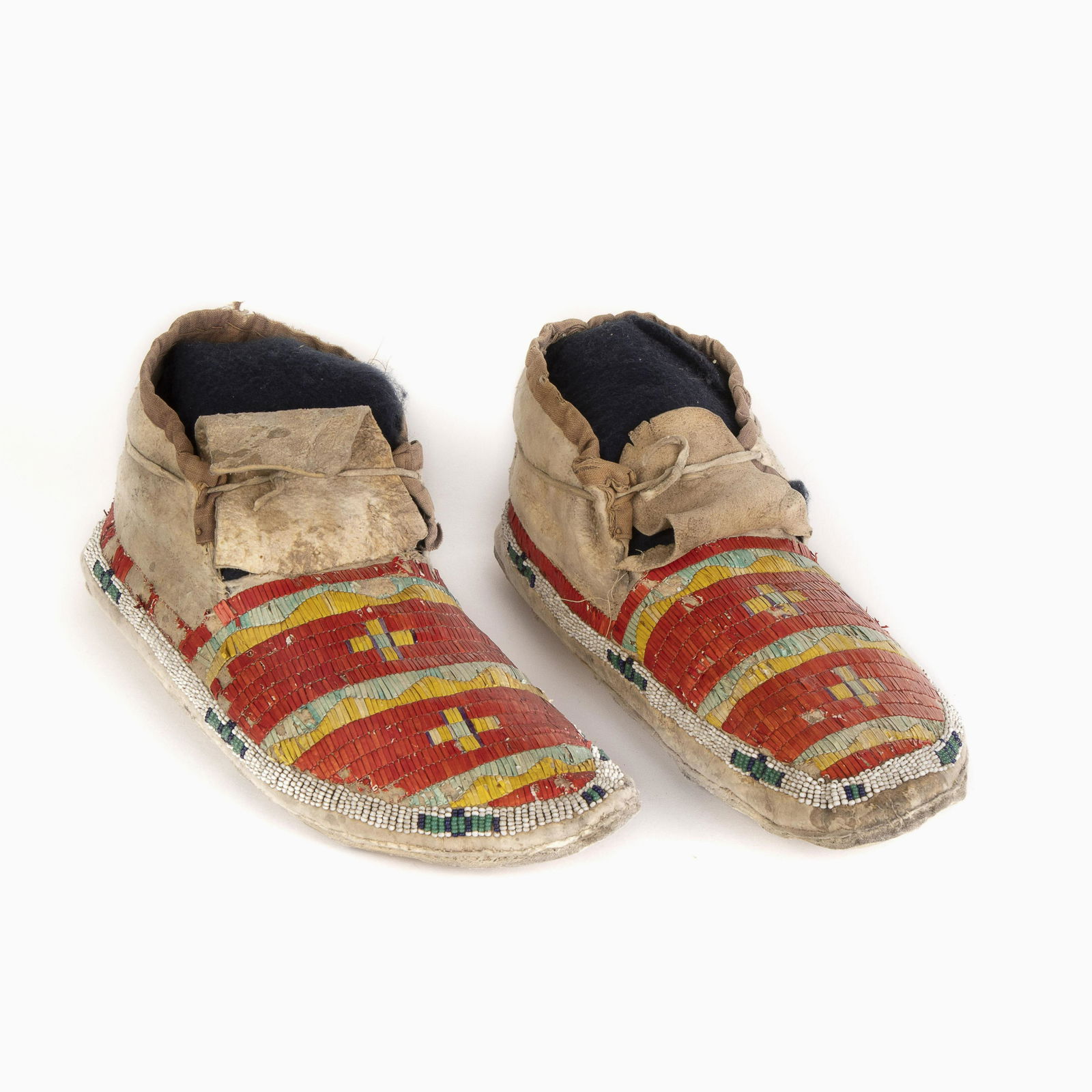 A Pair of Sioux Quilled and Beaded Hide Moccasins, ca.: Sioux Quilled and Beaded Hide Moccasins, ca. 1890thread and sinew-sewn, having a single lane of beadwork outlining sole in white, navy blue and green glass seed beadsvamps quilled in red, yellow, blue