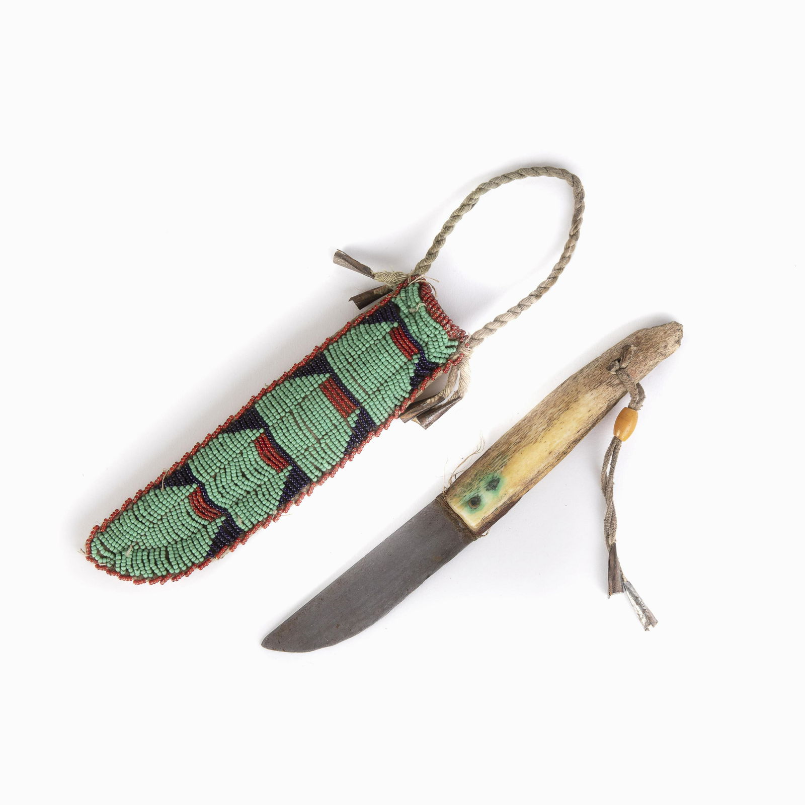 A Sioux Beaded Sheath and Knife, ca. 1920: Sioux Beaded Sheath and Knife, ca. 1920sinew sewn, having red, navy blue, and light green glass seed beadstin conesSheath: 7 x 2 in. (17.78 x 5.08 cm.), Hanging Length 10 in. (25.40 cm.) Private Colle