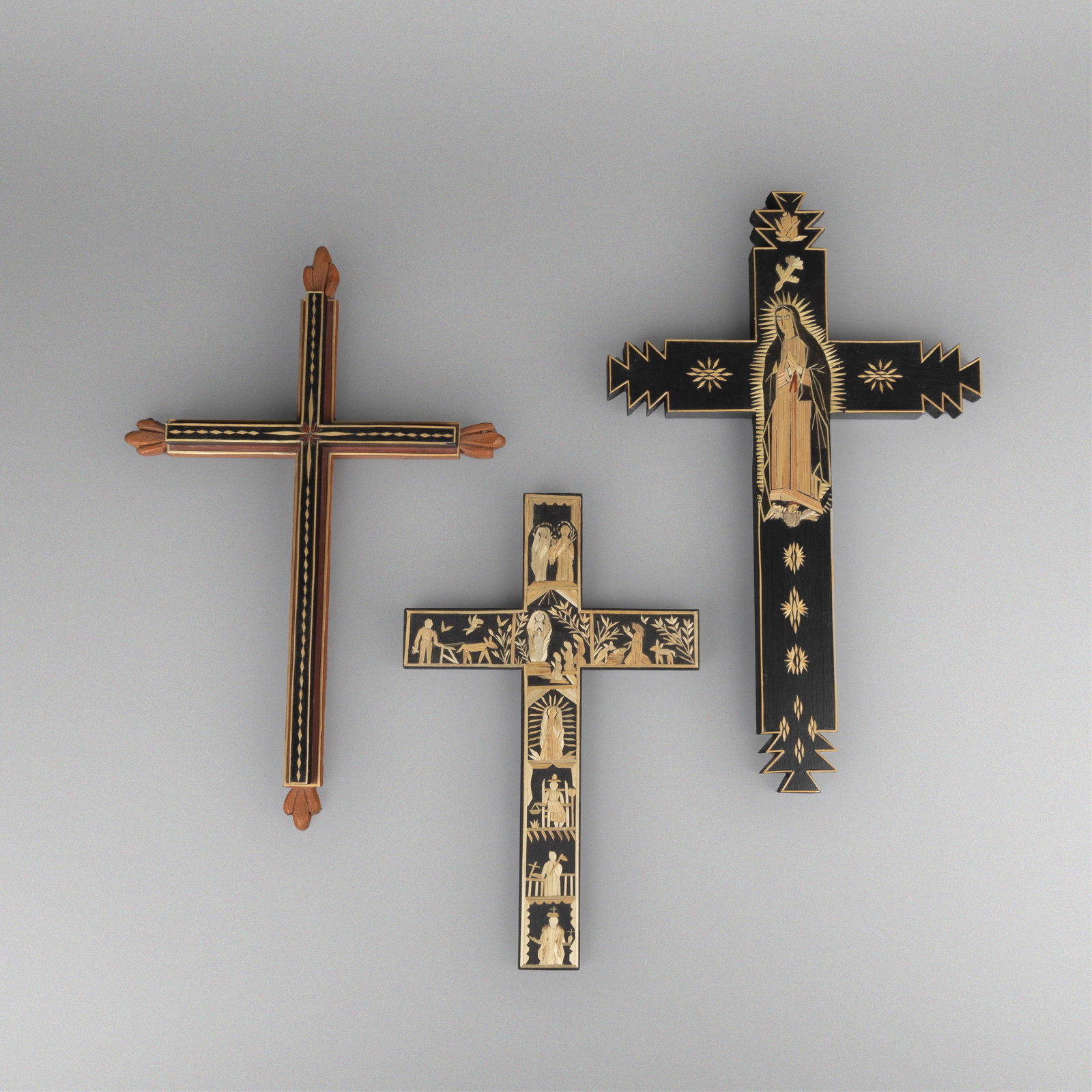 Charlie Sanchez + Diana Moya Lujan + Paula Rodriguez, Group of Three Straw Appliqué Crosses: Group of Three Straw Appliqué Crossescarved wood, pigments, strawCharlie Sanchez(b. 1947)Straw Applique Cross, 1994inscribed: ChaRliE SanchEz / 1994 / TOME N.M.15 1/2 x 10 1/8 x 1 in. (39.4 x 25.7 x
