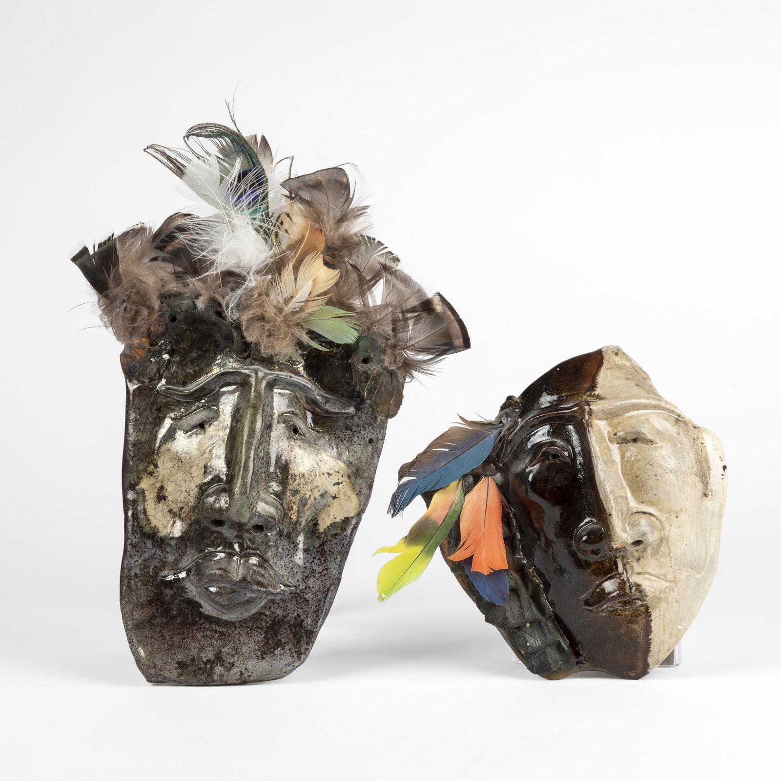 Fred Robert Wilson, Pair of Masks: Untitled (Large Mask), 2006 + Untitled (Two-Toned Mask), 2008: Fred Robert Wilson1932 - 2012Pair of Masks: Untitled (Large Mask), 2006 + Untitled (Two-Toned Mask), 2008glazed ceramic, featherslarger inscribed: FWiLsoN / 06 / WMNsmaller, including feathers: 8 x 8