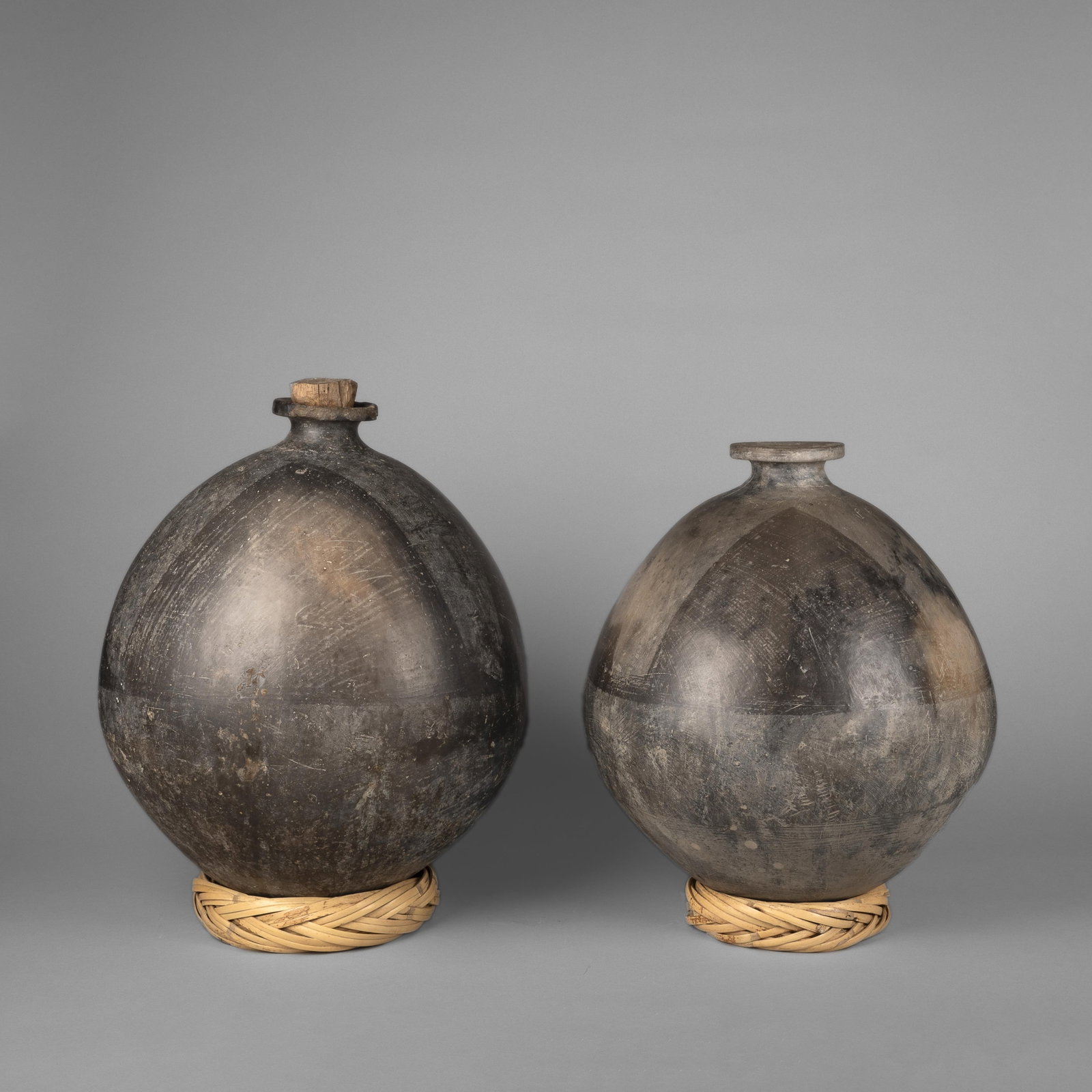 Two Mezcal Jugs: Two Mezcal Jugs fired clay, natural fiber bases one inscribed: AJ larger: 19 x 15 in. (48.3 x 38.1 cm.), smaller: 17 1/2 x 14 in. (44.5 x 35.6 cm.) Private Collection, New Mexico