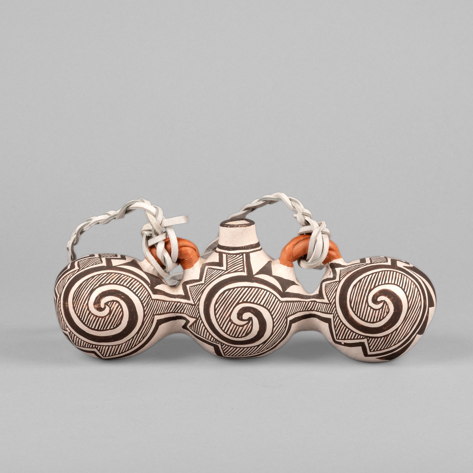 Juana Leno, Tri-Lobe Polychrome Canteen, 1998: Juana Leno Acoma, 1917 - 2000 Tri-Lobe Polychrome Canteen, 1998 fired clay, leather strap inscribed: J. LeNO / Acoma, NM / 1998 4 1/2 x 11 3/4 x 4 1/8 in. (11.4 x 29.8 x 10.5 cm.) Private Collection,