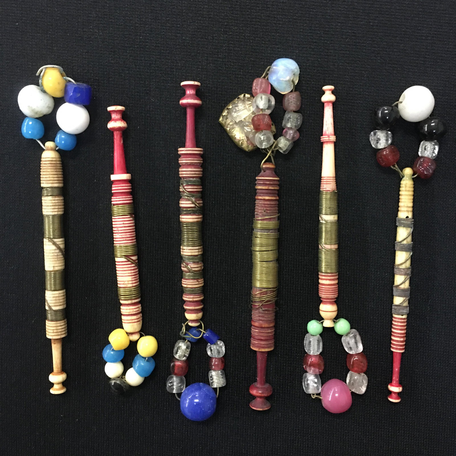 (6) Antique English Dyed Bone Wire Wrapped Bobbins: (6) Antique English Dyed Bone Wire Wrapped Bobbins. All spangled, wire wrapped with rings, pink dye. One head very slightly chipped and wire loose on another one. 3.5"-3.75"
