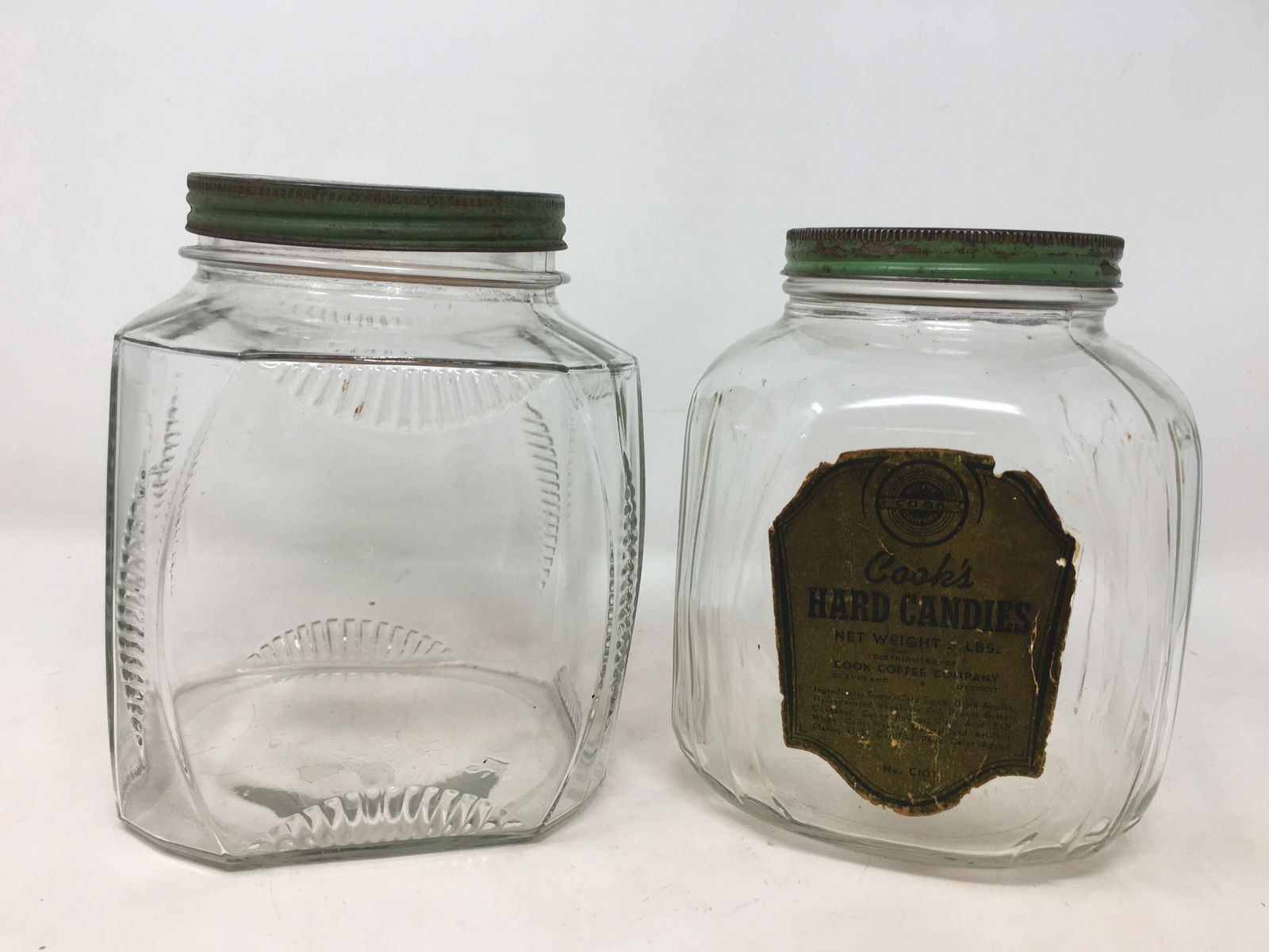 (2) Glass Counter Jars, Green Lids: (2) Glass Counter Jars, Green Metal Lids. One with paper label, Cook's Hard Candies, Cook Coffee Company. Larger 5" x 5" x 7"H
