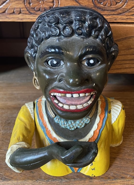 Black Americana Cast Iron Mech. Bank: "Dinah Bank" mechanical cast iron bank with lever. The coin is deposited in its mouth and the eyes roll back in the head. Has original paint. The back is marked Rd. No. 581285. 6 3/4" x 5 1/4"