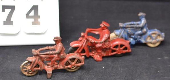 Three Cast Iron Motorcycle Cops: two red -  one w/  black rubber tires & one with metal  wheels, one