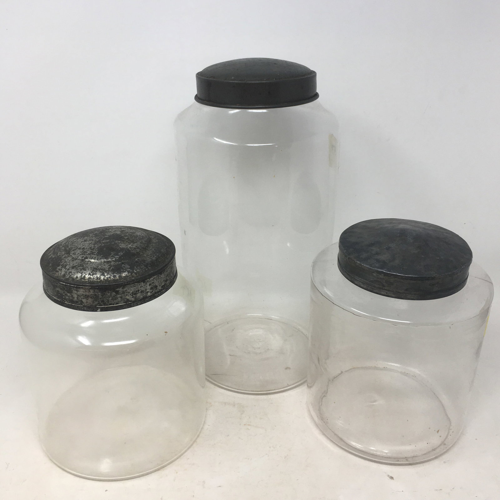 (3) Glass Counter Jars: (3) Glass Counter Jars with tin lids. Larger is 5.5"W x 12"H 2 smaller 7.5"H