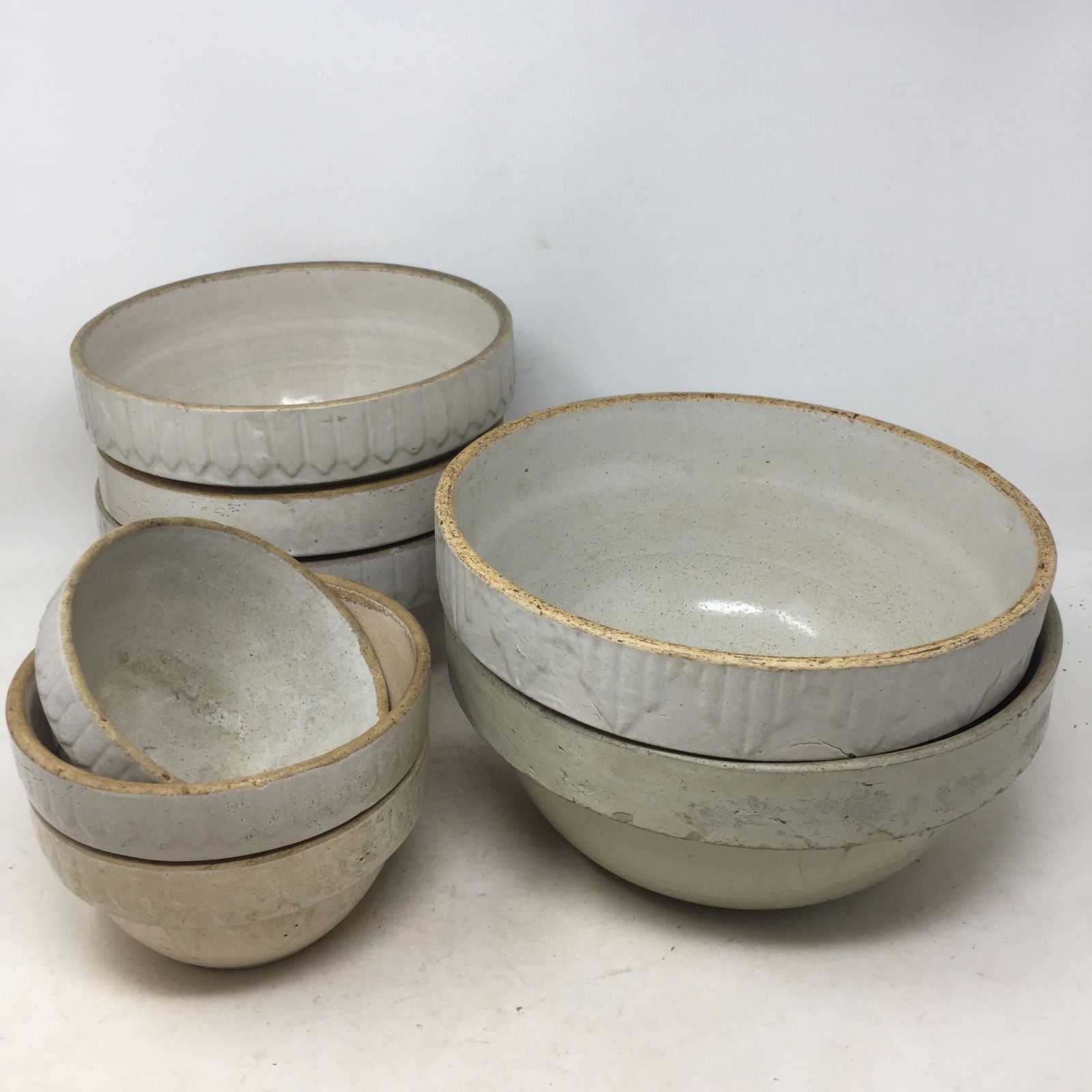 (8) White Stoneware Bowls: (8) White Stoneware Bowls, Various Sizes. Several picket fence pattern. One large bowl is Macomb Pottery. Largest 10"W x 5"H. Smallest 5.5"W x 3"H.