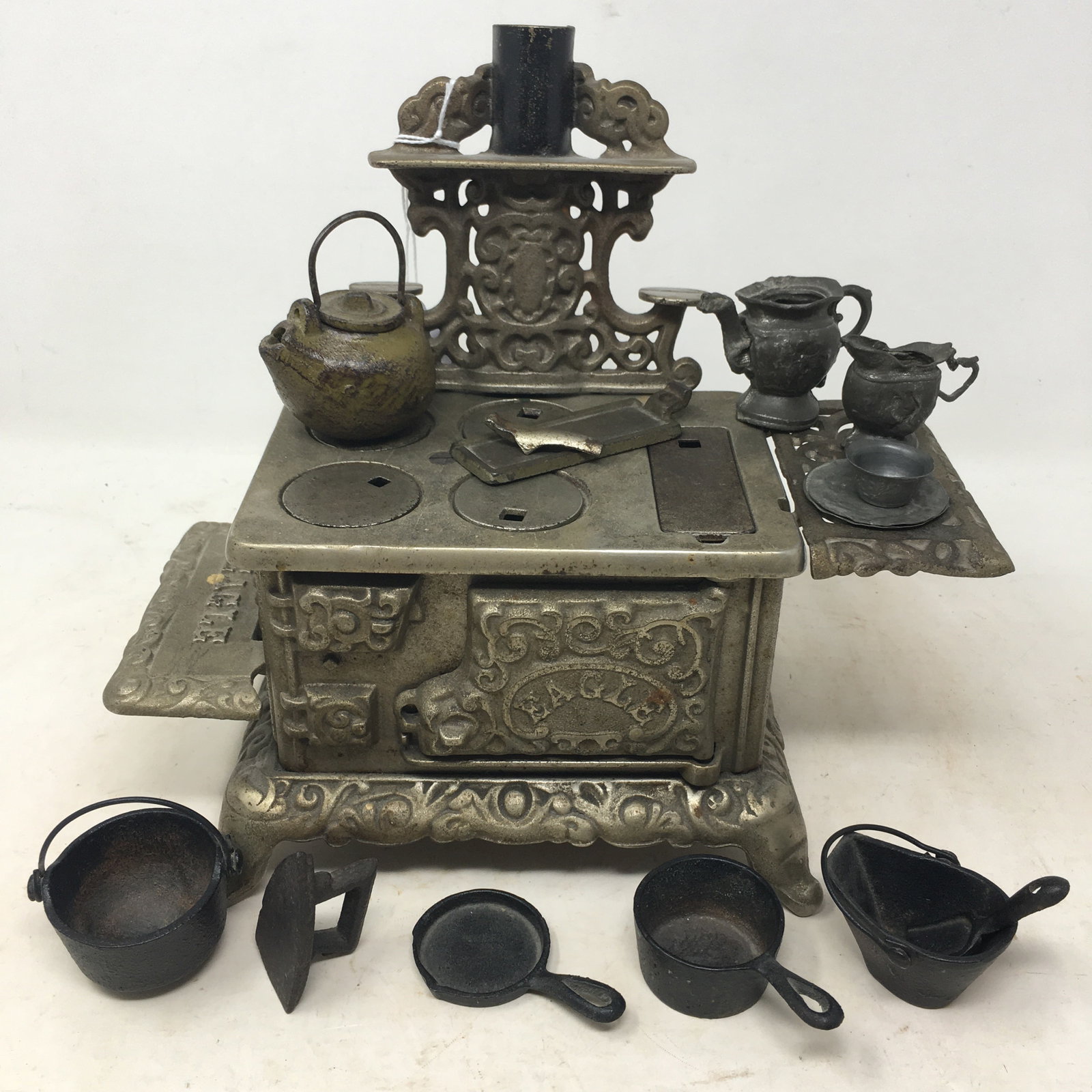 Cast Iron Toy Cookstove and Cookware: Cast Iron "Eagle" Toy Cookstove with Cookware: Tea Kettle, Coal Bucket & Shovel, Kettle, Pan, Skillet, Griddle, Iron & Cup. Has all 5 burner covers and cover lifter. Also tin coffee & tea pots, cup & 