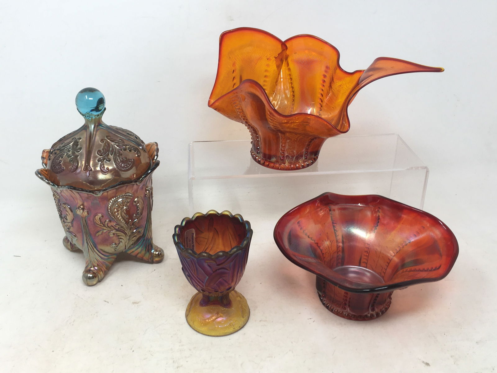 (4) Pieces St. Clair Carnival Glass: 4 Pieces St. Clair Carnival Glass. 1) Orange dish, beaded holly pattern. 2) Red dish, beaded holly pattern; 3) Amberina kingfisher footed toothpick holder; 4) Covered footed candy dish, Inverted fan &