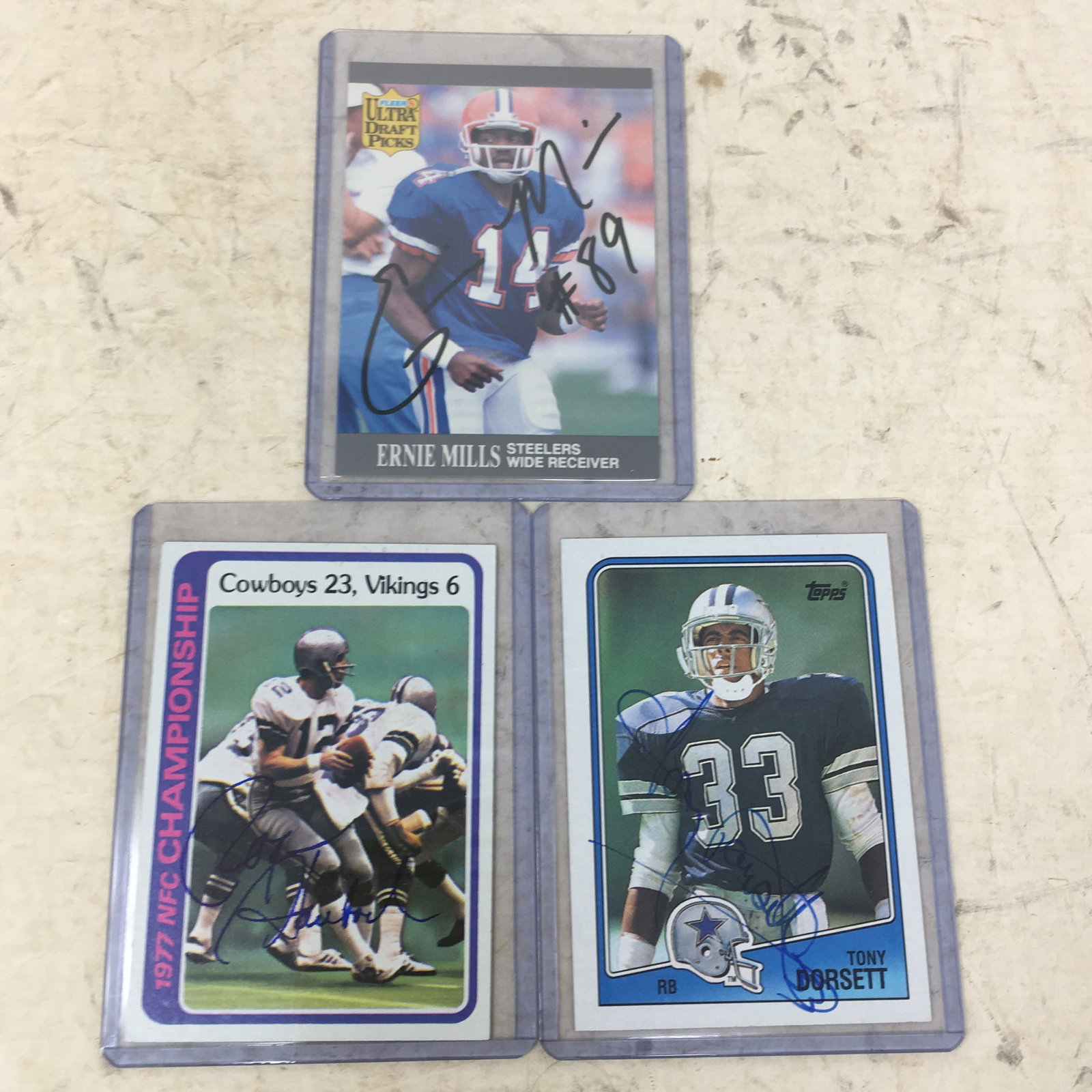 (3) Autographed Football Cards: (3) Autographed Football Cards. 1) 1978 Topps 1977 NFC Championship #166, signed by Roger Staubach; 2) 1988 Topps Tony Dorsett #262; 3) '91 Fleer Ultra Ernie Mills #290. No COAs.