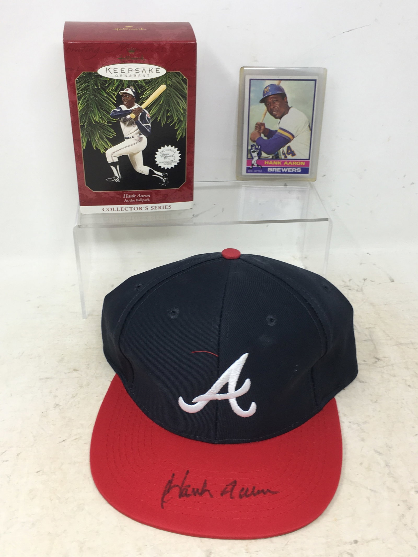 Hank Aaron Autographed Hat; 1976 Topps Card: Hank Aaron Autographed Hat, no COA. 1976 Topps Baseball Card; 1997 Hallmark Keepsake ornament.