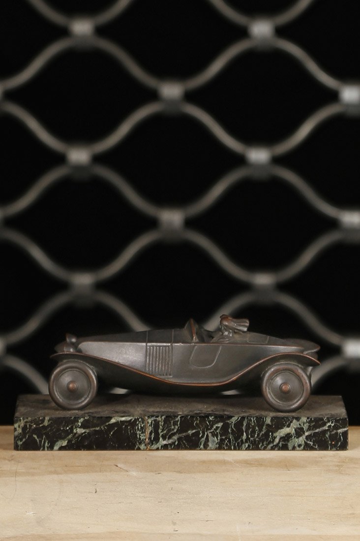 Couple dans un cabriolet circa 1930: A bronze patina sculpture figuring a man and a woman in a convertible H. 3 1/8 Inch L. 7 1/8 Inch P. 2 3/4 Inch D. 0 Inch En bronze a patine sombre, socle en marbre vert H. 8 cm L. 18 cm P. 7 cm