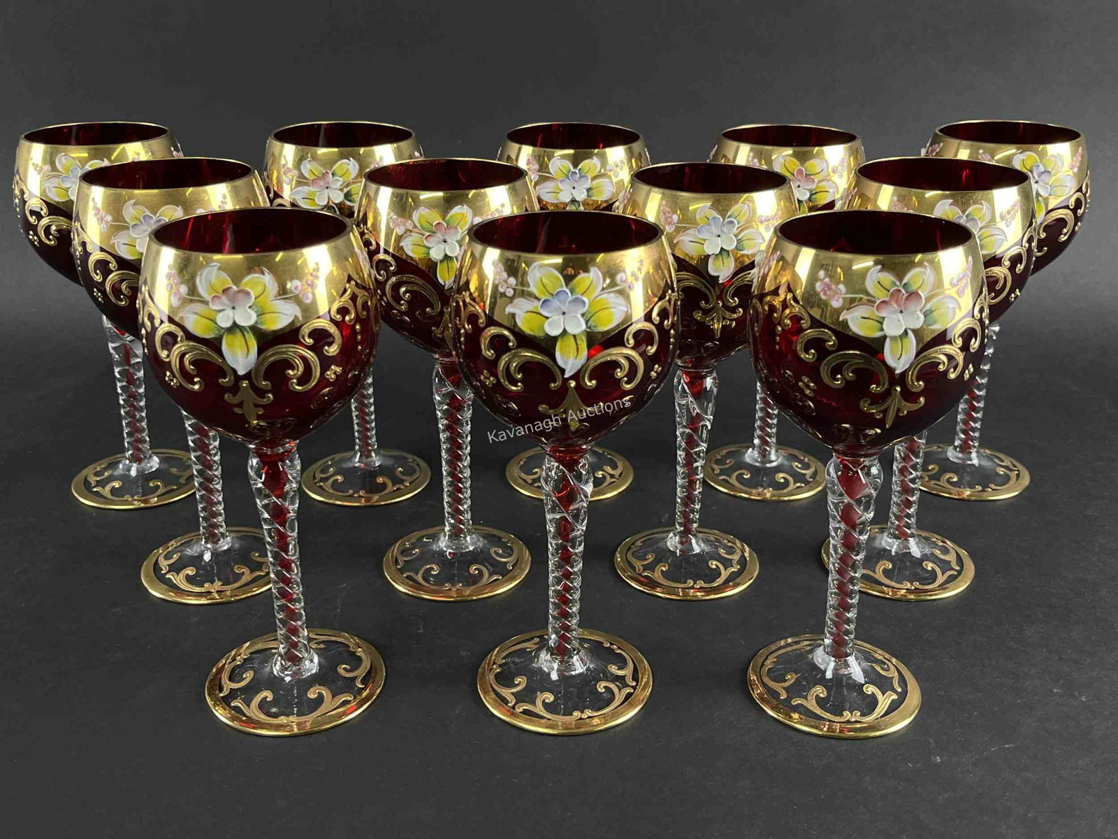 12 Murano Ruby Glass Gilded Flower Wine Glasses: Set of 12 Murano Ruby Glass Gilded Applied Flower Wine Glasses. Tall hock wine glasses of ruby red glass with twisted stem and hand applied gold and raised flower decoration. 7.5 inches H.