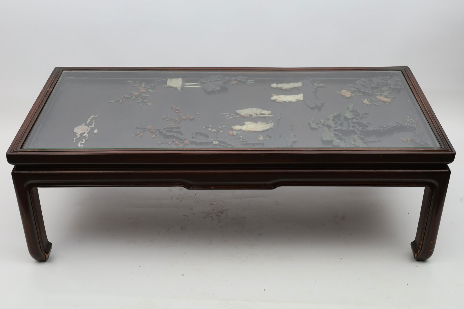 Chinese Antique Jade Precious Stone Panel Table: Chinese antique panel set with carved jade and other semi-precious stones as a garden scene with temple and figures, later mounted as a coffee table with glass top. 25.5 x 52.5 x 17 inches H.
