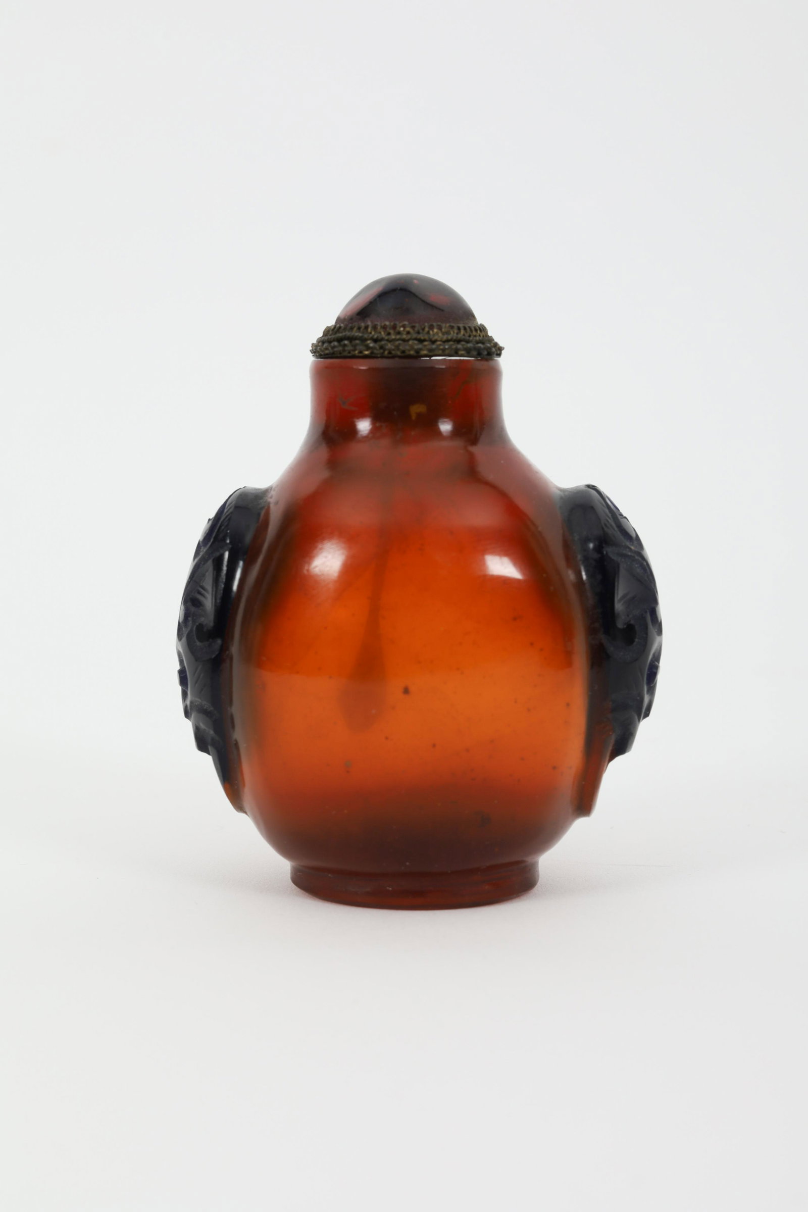 Antique Chinese Black and Amber Glass Snuff Bottle: Antique Chinese clear amber coloured glass snuff bottle with black glass overlay on the sides cut with dragon faces, polished rim on base. 3 inches H.