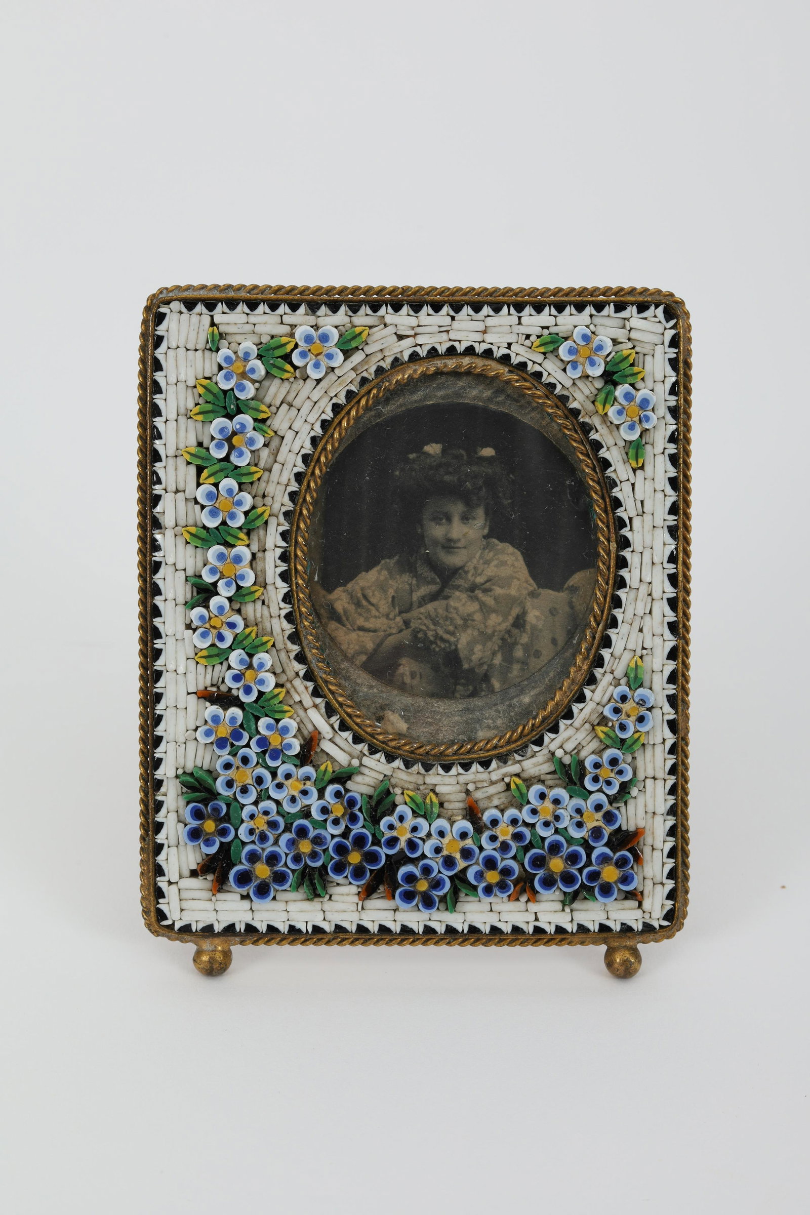 Antique Victorian Micro Mosaic Floral Frame Italy: Antique Victorian small photo frame on two ball feet with a rope banding around the rim of the frame and inner area for the photo. The front of the frame set with detailed micro mosaic design of blue 