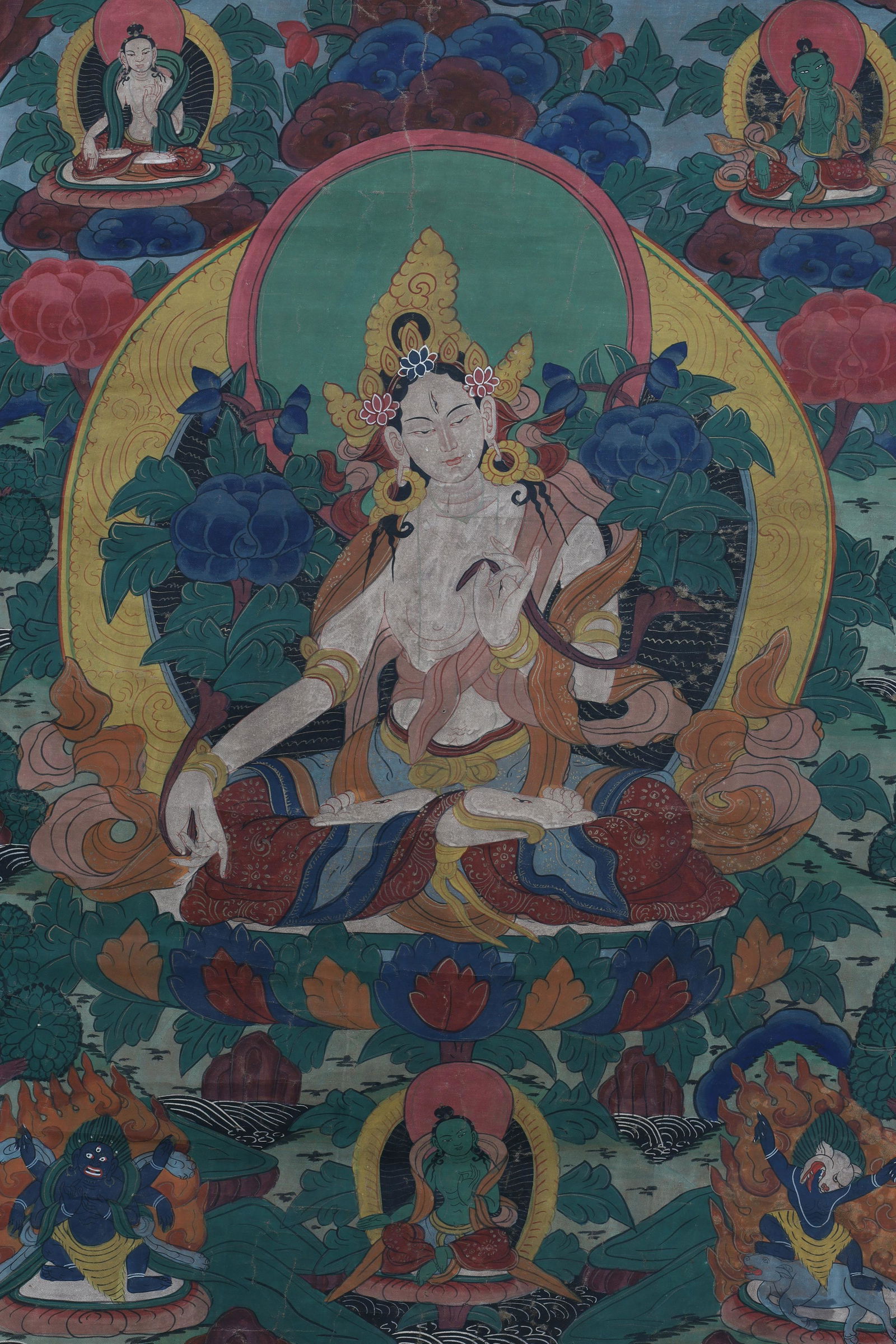 Tibetan Antique Thangka White Tara Protection: Antique Tibetan thangka with hand painted detailed design showing White Tara in the centre, left hand in the Abhaya Protection Mudra, with other deities below and above, with silk border; this thangka